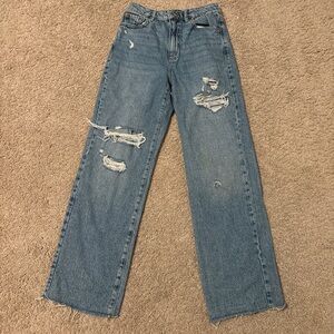 High-waisted, wide-leg blue jeans with a distressed, ripped look